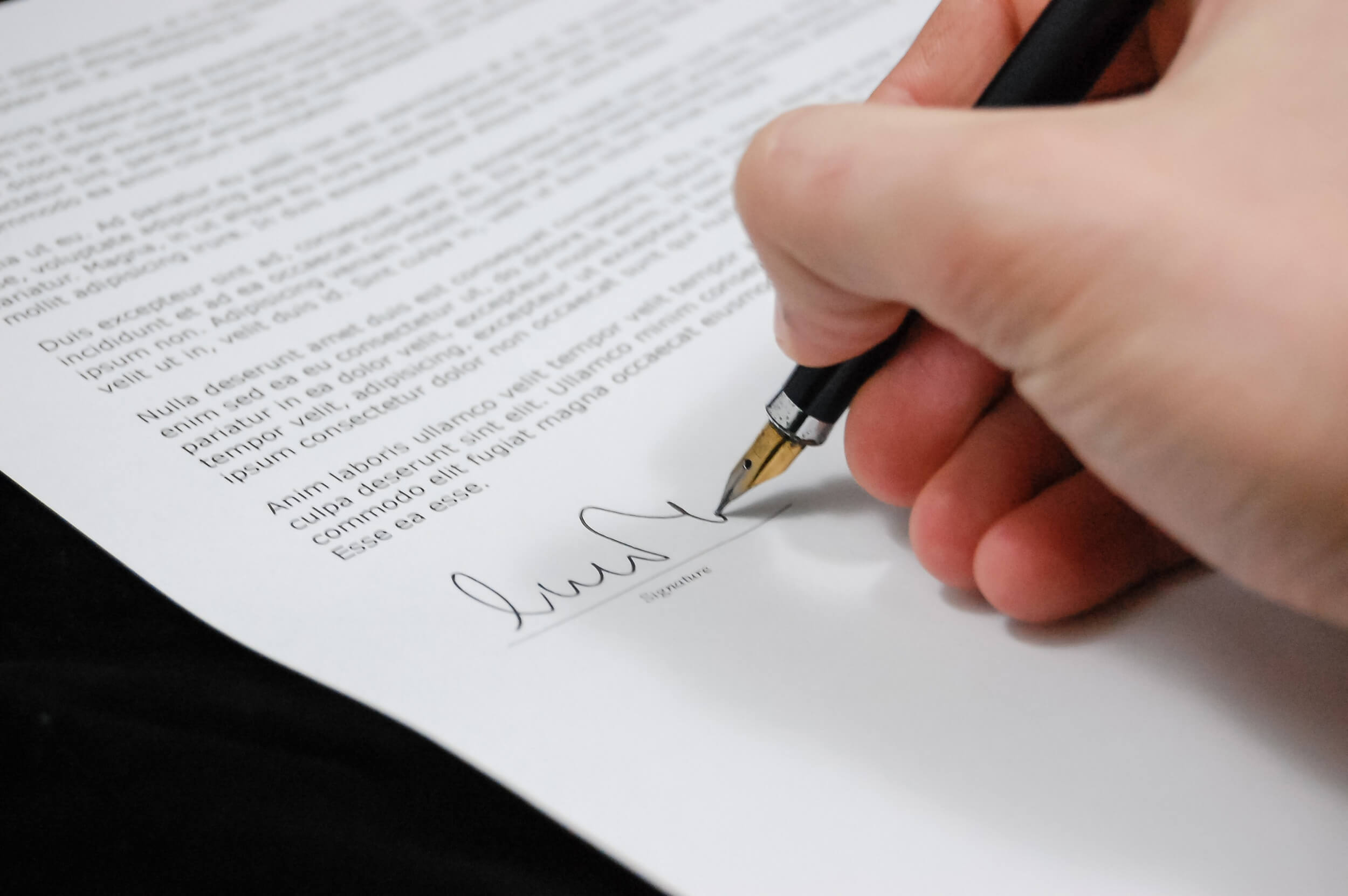 A person signs their signature on a document.
